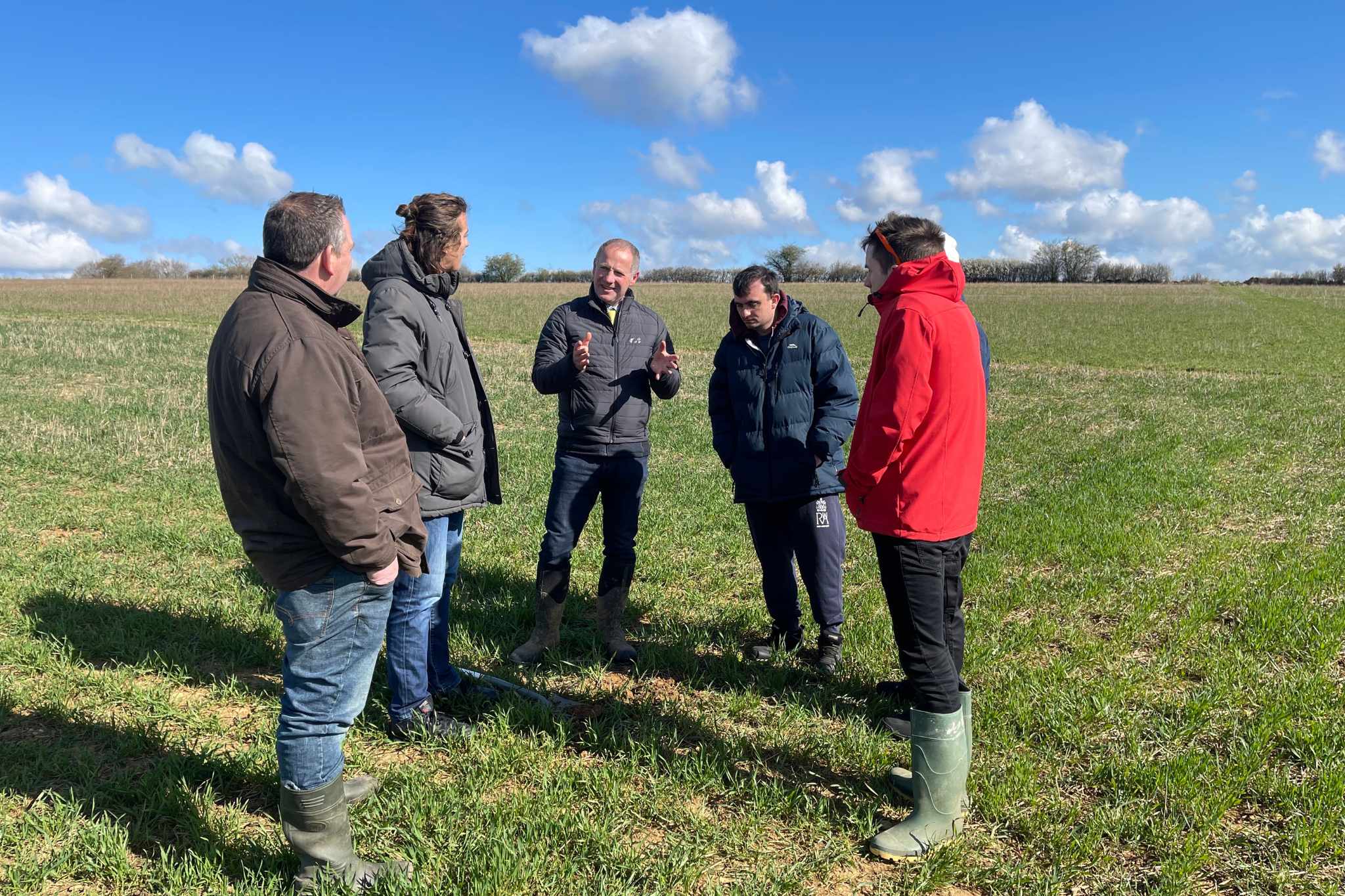 Group of people standing in a field during an on-farm sustainability training session.