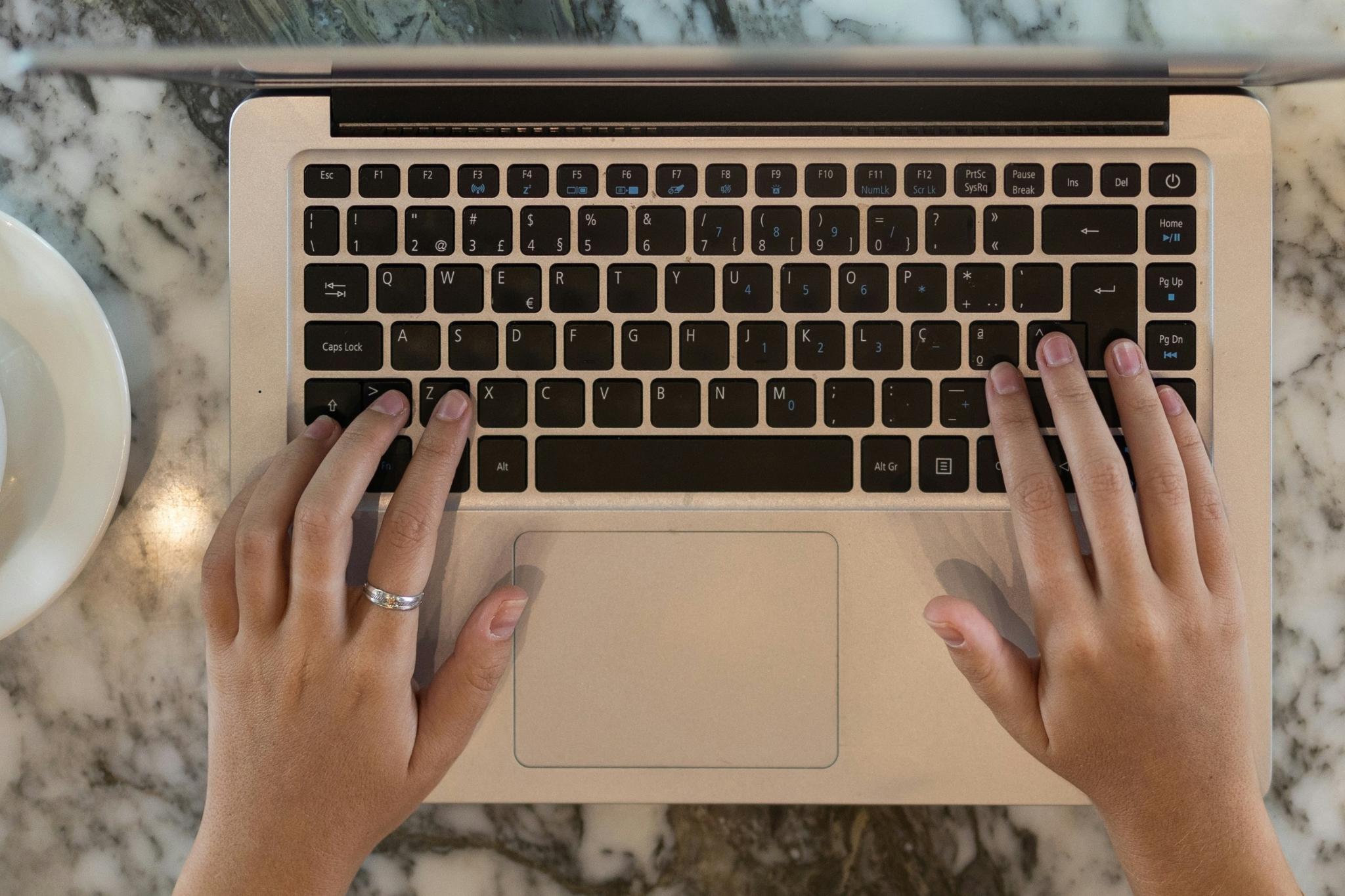 Person typing on a laptop representing online sustainability training modules.
